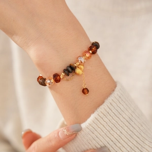 Détail du bracelet œil de tigre avec glands dorés et perles d'ambre polies