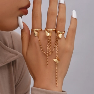 Close-up of golden finger bracelet with rings and hanging butterfly pendants on a model