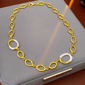 Detail of gold necklace featuring white enamel oval links displayed on a jewelry box