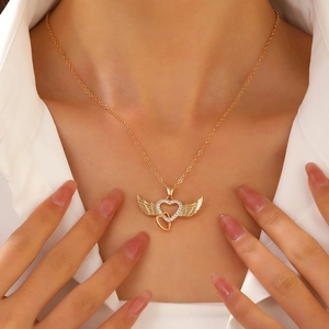 Detail shot of golden angel wing heart pendant necklace with rhinestones on model neck