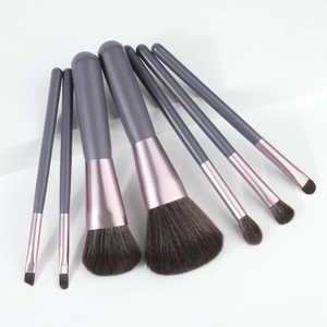 Detailed view of 7-piece makeup brush set with grey handles and purple ferrule on white blocks