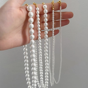 Detail view of four white pearl necklaces in different sizes with gold clasps