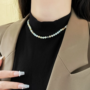 Close-up of light blue and gold square beaded necklace worn on a model neck