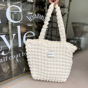 Close-up of ivory white puffy cloud tote bag with 3D bubble texture and logo patch