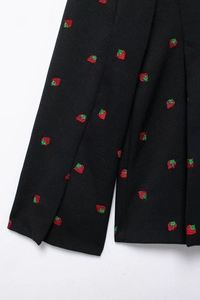 Vue macro détaillée des broderies fraises rouges sur le tissu en laine mélangée noir