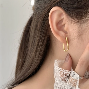 Minimalist gold U-shaped silver earrings worn on ear with elegant lace sleeve background