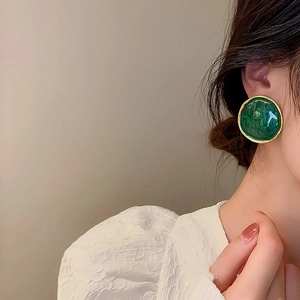 Retro emerald green enamel round stud earrings with gold rim worn by a model