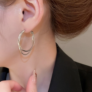 Gros plan de boucles d'oreilles créoles doubles en argent portées à l'oreille au fini poli
