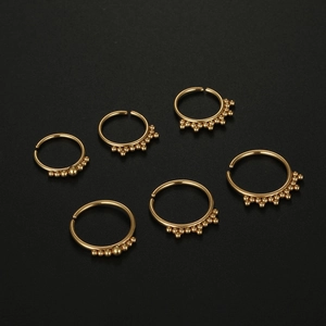 Set of six golden 316L stainless steel nose rings with small bead accents on black background