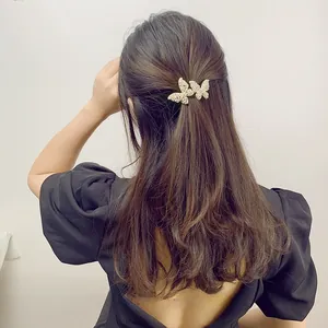 Detail view of double butterfly hair clip with white pearls and rhinestones on black hair
