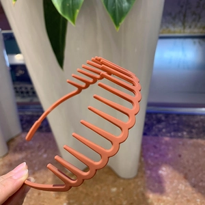 Detail of matte orange-pink hairband showing internal anti-slip teeth and frosted texture