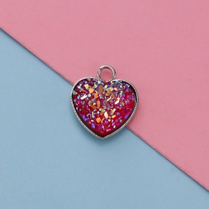 Macro view of a 13mm heart-shaped red glitter pendant with silver metal frame