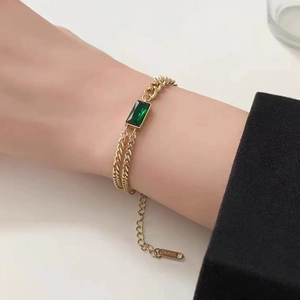 Detailansicht eines vergoldeten Edelstahl-Armbands mit einem grünen quadratischen Edelstein