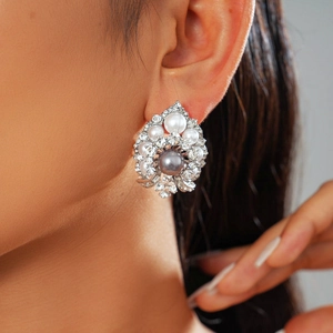 Detailed view of large cluster flower stud earring with grey pearl and crystals on model