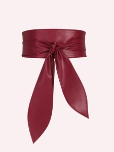 Close-up of deep red wide waist belt with elegant bow tie knot in soft leather