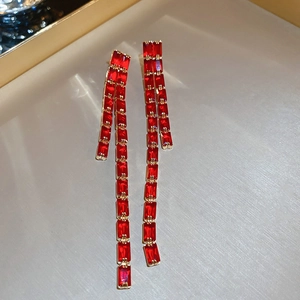 Detail of red rectangular gemstones set in gold tassel earrings with elegant drapes