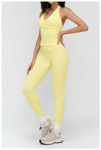 Detail of yellow yoga set featuring halter neck top and high-waist leggings for fitness