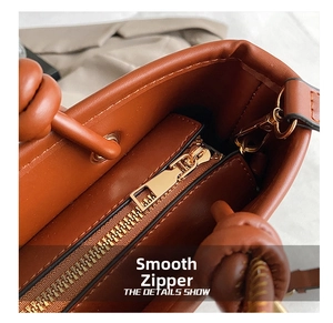 Detail view of smooth golden metal zipper and durable D-ring on brown tote bag