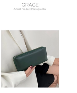 Nahaufnahme einer grünen Lederbrieftasche mit Reißverschluss, von einem Modell gehalten