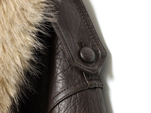 Close-up of brown leather jacket featuring textured grain and fluffy detachable fur collar