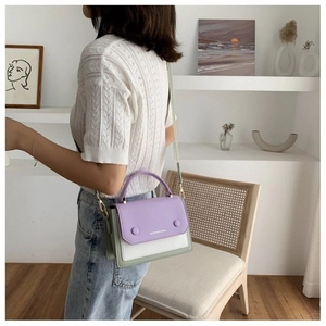 Detail of color-block crossbody bag with purple flap, white body and green accents