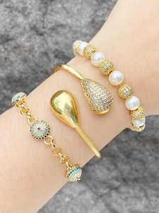 Detail of gold evil eye bracelets and pearl jewelry set with sparkling zircon on wrist