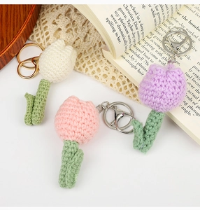 Detailed view of handmade knitted tulip flower keychains in white, pink and purple yarn