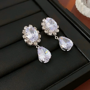 Macro shot of silver teardrop earrings with sparkling zircon stones on black display