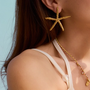 Luxury gold starfish earrings for women with natural textured finish on blue background
