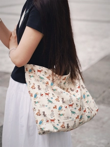 Artistic white cotton tote bag with colorful dog prints worn over the shoulder outdoors
