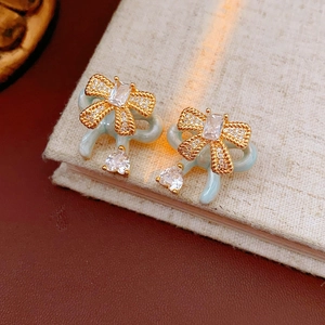 Detailed close-up of blue bow earrings with gold rope texture and heart-shaped zircons