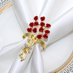 Close-up of red rose napkin ring with gold stem and rhinestone bow on white fabric
