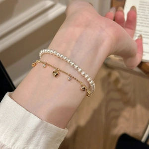 Bracciale a doppio strato con perle finte bianche e ciondolo a cuore dorato con pavé di pietre
