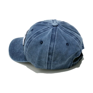 Detailed view of washed denim baseball cap with premium embroidery and metal buckle