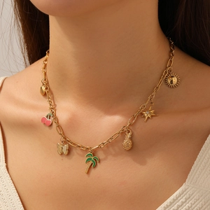 Gold-plated necklace featuring colorful enamel fruit and palm tree pendants on a model