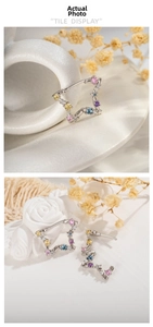 Detailed view of silver star earrings with multi-colored cubic zirconia on white background