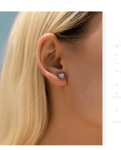Close-up of sparkling blue heart stud earrings worn by a model in soft lighting