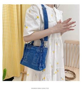 Blue denim tote bag detail showing contrast stitching and detachable wide shoulder strap