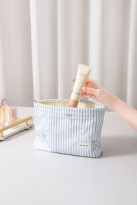Détail d'une trousse à maquillage rayée bleue avec étiquette H&R BAG et zip métallique
