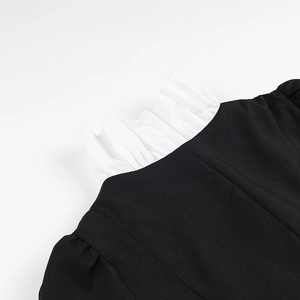Close-up detail of white ruffle stand collar on a black long sleeve patchwork dress