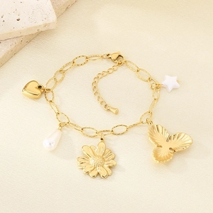 Detail view of gold charm bracelet with heart, pearl, flower, and star pendants