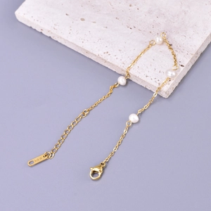Macro detail of gold lobster clasp and K18 engraved tag on freshwater pearl necklace