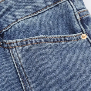 Détail du jean bleu délavé vintage avec rivets métalliques et double couture robuste