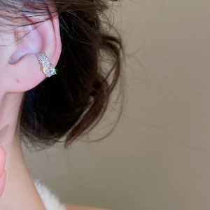 Close-up of a silver zircon ear cuff featuring a large oval stone on model's ear cartilage