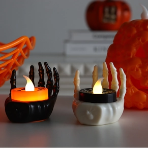 Close-up of Halloween LED skull hand candle lights in black and white on a festive table