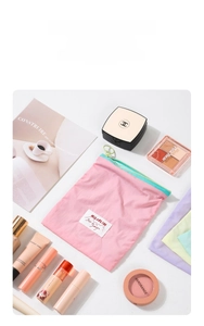 Close-up of pink nylon makeup bag with light green zipper and MILOBLISS brand tag