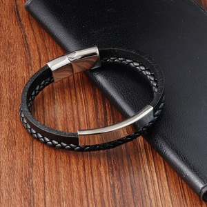 Men's black braided leather bracelet with silver magnetic clasp on a wooden desk