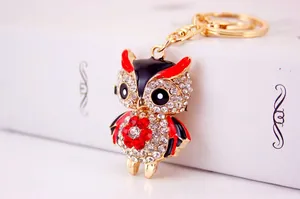 Detail of owl keychain with sparkling rhinestones and red enamel wings on metal