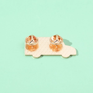 Détail du dos de la broche médicale en métal doré avec doubles fermoirs papillon et texture