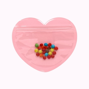 Close-up of a pink heart-shaped resealable plastic pouch filled with colorful candy
